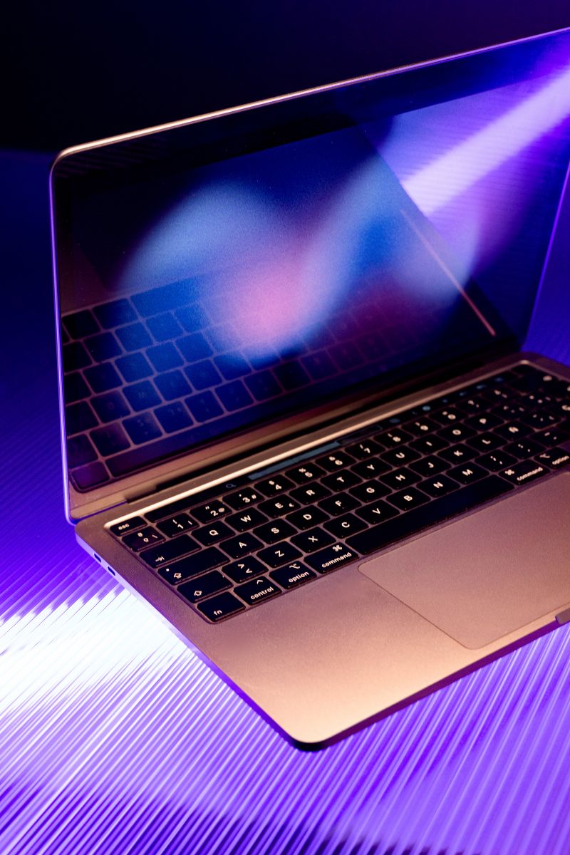An open laptop lit by violet and blue light