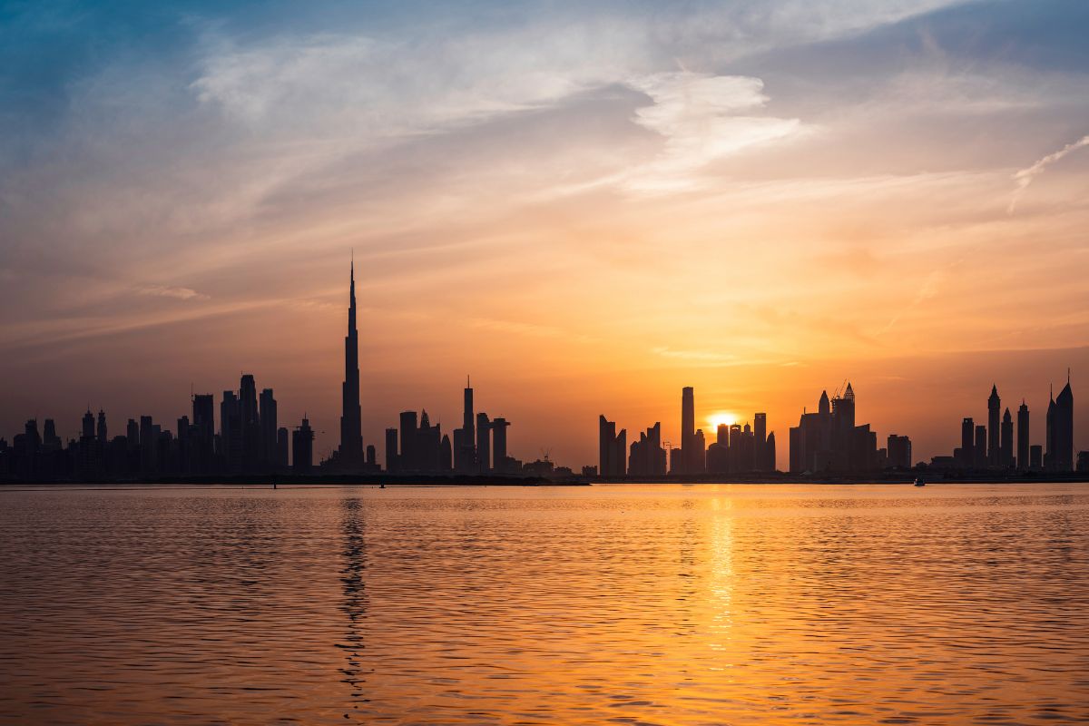 A city skyline at sunset, reflected in calm water